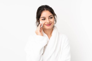 Beyaz arka planda, makyajını silmek için pamuklu ped kullanan beyaz tenli bir kadın.