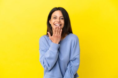 Sarı arka planda izole edilmiş genç beyaz kadın mutlu ve gülümsüyor.