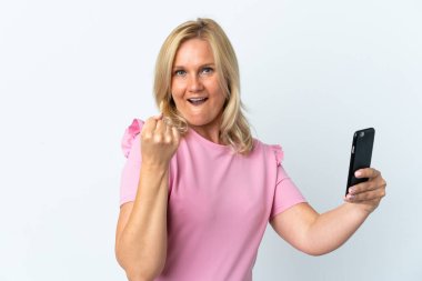 Middle age using mobile phone isolated on white background celebrating a victory