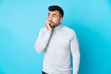 İzole edilmiş mavi arka planı olan beyaz bir adam biraz gergin.