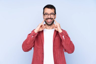 Young caucasian man wearing corduroy jacket over blue background smiling with a happy and pleasant expression