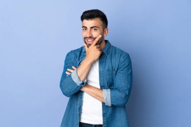 İzole edilmiş mavi arka planı olan beyaz bir adam mutlu ve gülümsüyor.