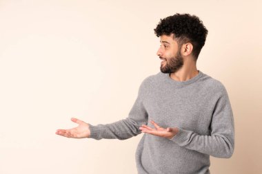 Faslı genç bir adam bej arka planda izole edilmiş.