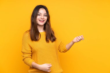Sarı arka planda izole edilmiş beyaz bir kadın gitar hareketi yapıyor.