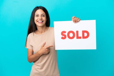 Arka planda izole edilmiş genç bir kadın. Elinde yazılı bir pankart var ve onu gösteriyor.