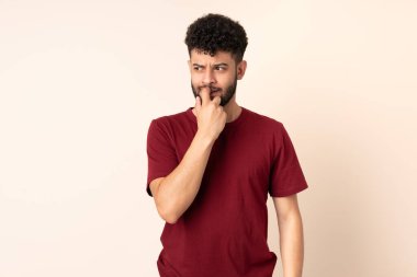 Young Moroccan man isolated on beige background nervous and scared