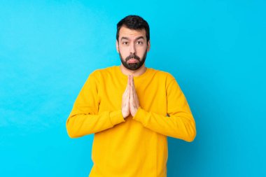 İzole edilmiş mavi geçmişi olan genç beyaz bir adam avuç içlerini bir arada tutuyor. İnsan bir şey ister.