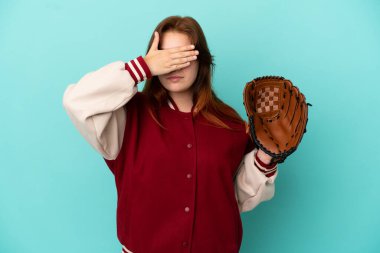 Young redhead woman playing baseball isolated on blue background covering eyes by hands. Do not want to see something