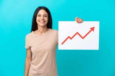 Arkaplanda mutlu bir ifadeyle büyüyen bir istatistik ok sembolü taşıyan bir tabela tutan izole edilmiş genç bir kadın.