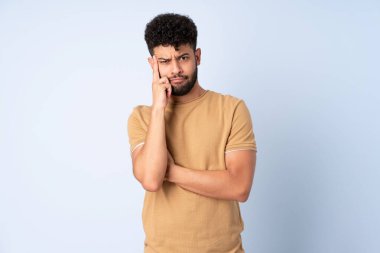 Genç Faslı bir adam mavi arka planda izole edilmiş bir fikir düşünüyor.