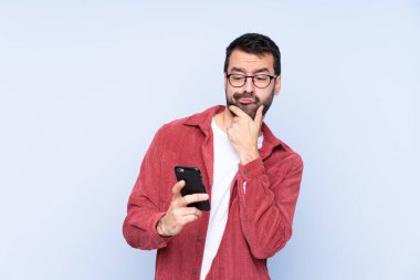 Young caucasian man wearing corduroy jacket over blue background thinking and sending a message