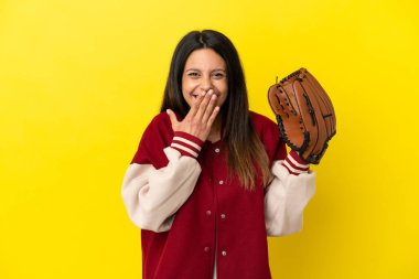 Beyzbol oynayan beyaz bir kadın, sarı arka planda izole edilmiş mutlu ve ağzı kapalı gülümsüyor.