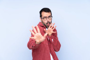 Young caucasian man wearing corduroy jacket over blue background nervous stretching hands to the front