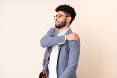 Young business Moroccan man isolated on beige background suffering from pain in shoulder for having made an effort