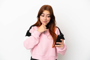 Genç kızıl saçlı kadın beyaz arka planda izole edilmiş düşünüyor ve bir mesaj gönderiyor.