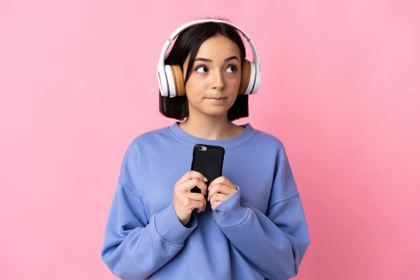 Młoda Kaukaska Kobieta Odizolowana Różowym Tle Słuchanie Muzyki Telefonu Komórkowego — Zdjęcie stockowe