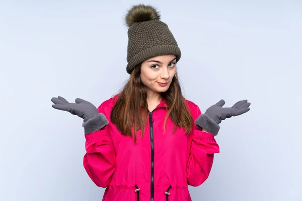 Young Girl Winter Hat Isolated Blue Background Having Doubts While — Φωτογραφία Αρχείου