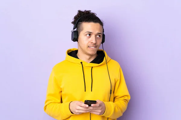 Caucasian Man Isolated Purple Background Listening Music Mobile Thinking — ストック写真