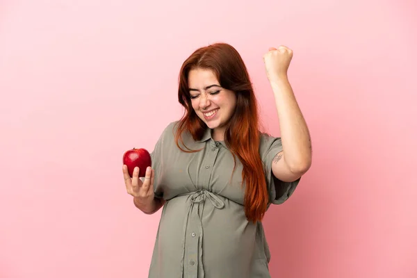 Young Redhead Caucasian Woman Isolated Pink Background Pregnant Holding Apple — Stock Fotó