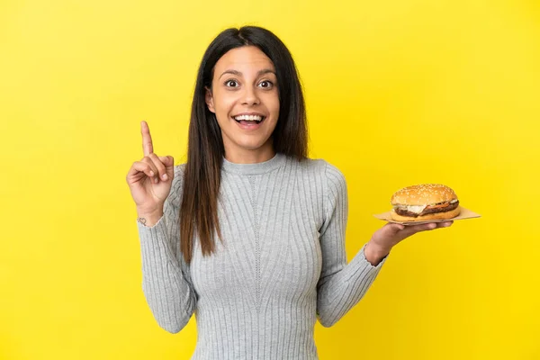 Young Caucasian Woman Holding Burger Isolated Yellow Background Intending Realizes — Stock Photo, Image