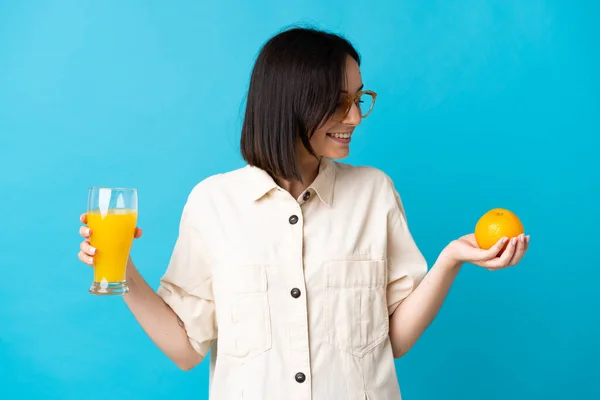 Ung Kaukasisk Kvinna Isolerad Blå Bakgrund Håller Apelsin Och Apelsinjuice — Stockfoto