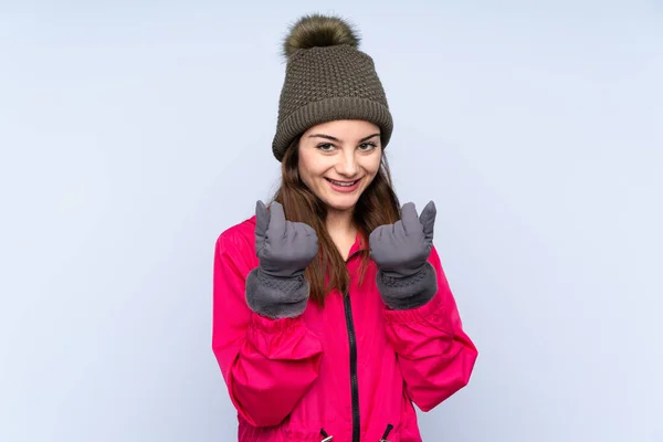 Young Girl Winter Hat Isolated Blue Background Making Money Gesture — Φωτογραφία Αρχείου