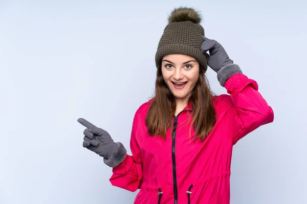 Young Girl Winter Hat Isolated Blue Background Surprised Pointing Finger — Φωτογραφία Αρχείου