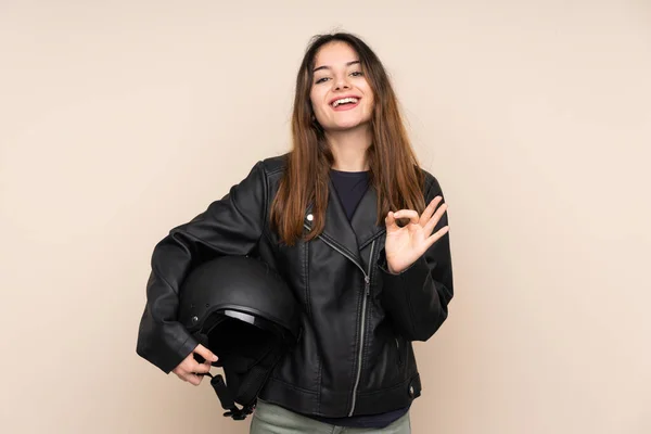 指でOkサインを示すベージュの背景に隔離されたオートバイのヘルメットを持つ女性 — ストック写真