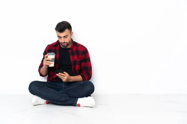 Yerde Oturan Yakışıklı Genç Bir Adam Elinde Kahve Bir Cep — Stok fotoğraf