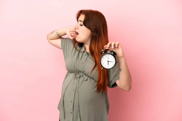 Young Redhead Caucasian Woman Isolated Pink Background Pregnant Holding Clock — Φωτογραφία Αρχείου
