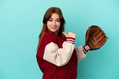 Young redhead woman playing baseball isolated on blue background proud and self-satisfied