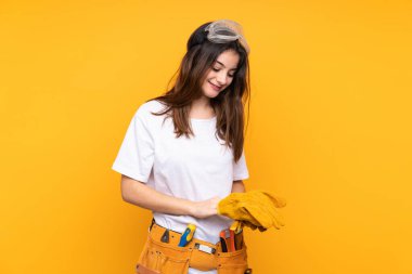 Sarı arka planda izole edilmiş genç elektrikçi kadın.
