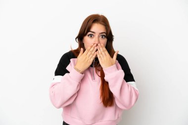Beyaz arka planda izole edilmiş genç, kızıl saçlı bir kadın elleriyle ağzını kapatıyor.