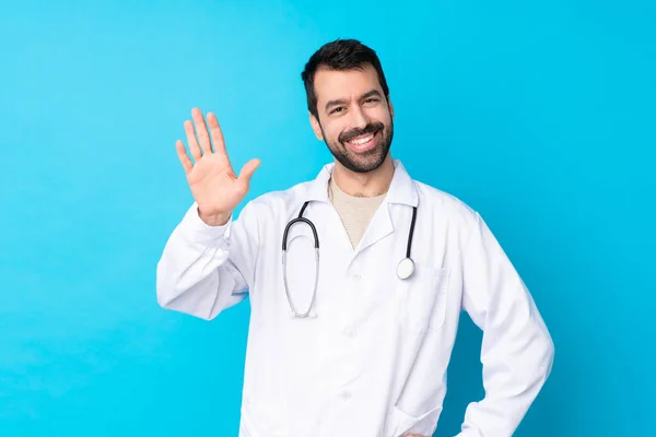 Young Caucasian Man Isolated Background Wearing Doctor Gown Saluting —  Fotos de Stock