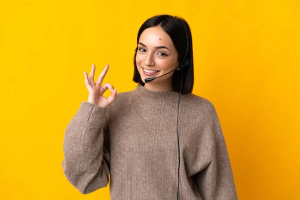 若いテレマーケティング担当者の女性は 指でOkサインを示す黄色の背景に隔離 — ストック写真