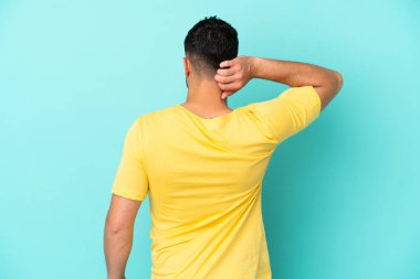 Genç Arap adam arka planda mavi arka planda izole edilmiş ve düşünüyor