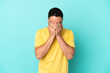 Genç Arap adam mavi arka planda izole edilmiş, yorgun ve hasta bir ifadeyle.