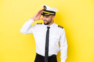 Arap uçak pilotu, sarı arka planda izole edilmiş, gülümsüyor.