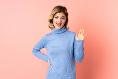 Pembe arka planda izole edilmiş genç Rus kadın parmaklarıyla tamam işareti gösteriyor.