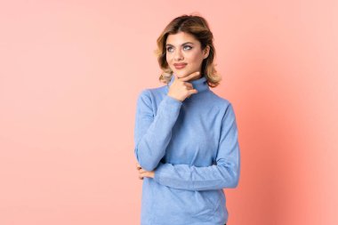 Genç Rus kadın pembe arka planda izole edilmiş gülümserken yukarı bakıyor