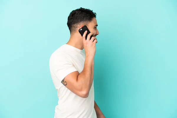 Młody Arabski Człowiek Odizolowany Niebieskim Tle Prowadzenie Rozmowy Telefonu Komórkowego — Zdjęcie stockowe