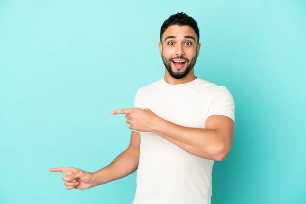 Mladý Arabský Muž Izolovaný Modrém Pozadí Překvapen Ukazuje Stranou — Stock fotografie