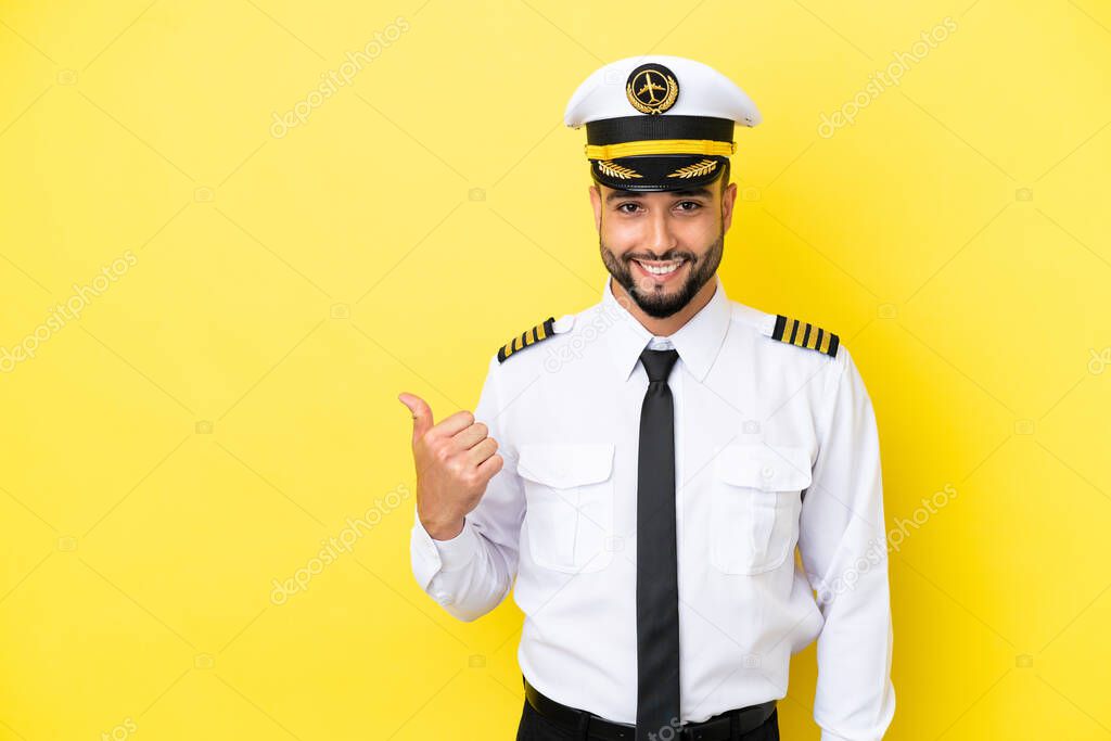 Airplane arab pilot man isolated on yellow background pointing to the side to present a product