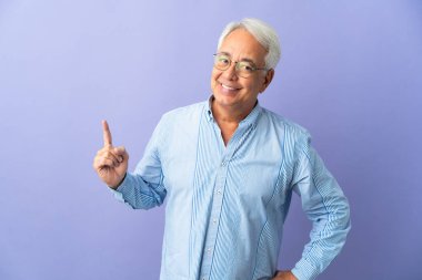 Mor arka planda izole edilmiş orta yaşlı Brezilyalı bir adam en iyinin işareti olarak parmağını kaldırıyor.