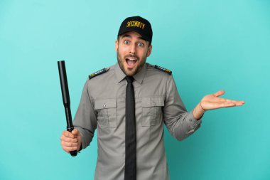 Genç güvenlik görevlisi mavi arka planda izole edilmiş, şok olmuş bir yüz ifadesi var.