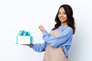 Pasta şefi, izole edilmiş beyaz arka plan üzerinde büyük bir pasta tutuyor. Davet etmek için ellerini yana uzatıyor.