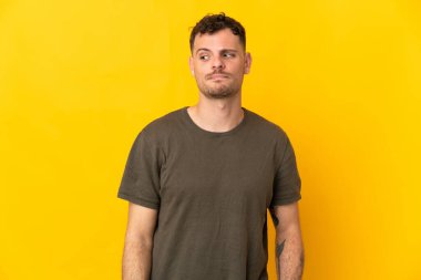 Sarı arka planda izole edilmiş beyaz, yakışıklı genç bir adam.
