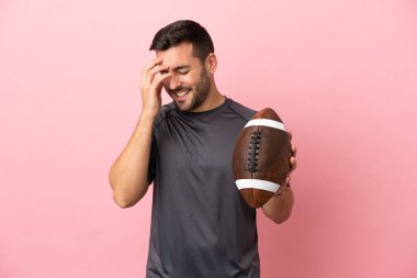 Pembe arka planda izole edilmiş rugby oynayan beyaz bir adam gülüyor.