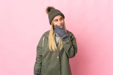 Pembe arka planda izole edilmiş, kış şapkalı genç kadın kuşkuları var.
