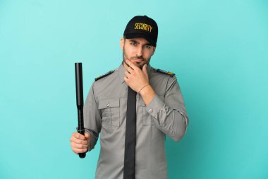 Genç güvenlik elemanı mavi arka planda izole edilmiş düşünüyor.